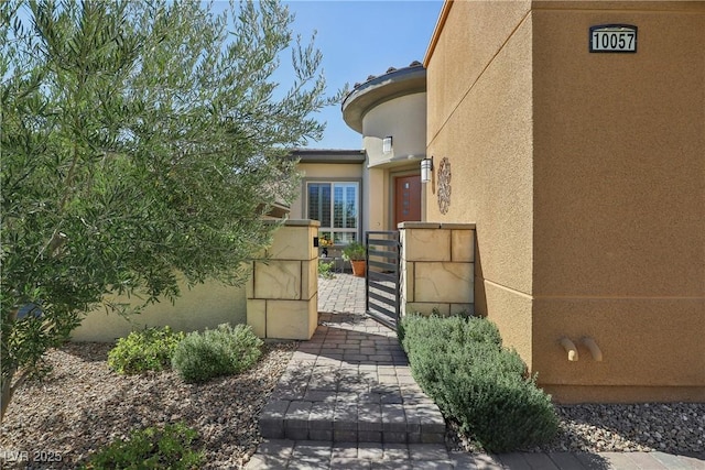 exterior space with stucco siding, fence, and a gate