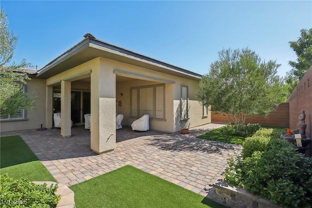 back of property with a patio area, stucco siding, and fence