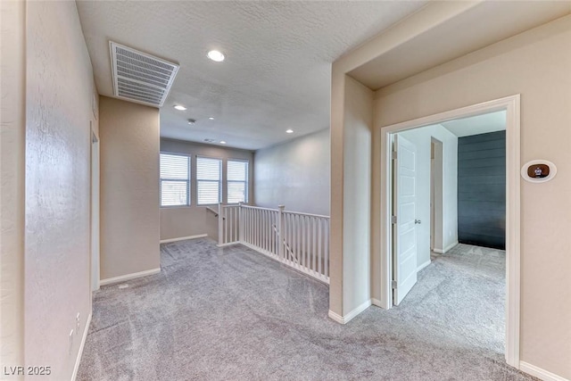 corridor featuring light carpet and a textured ceiling