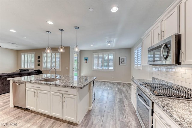 kitchen featuring white cabinetry, appliances with stainless steel finishes, sink, and an island with sink