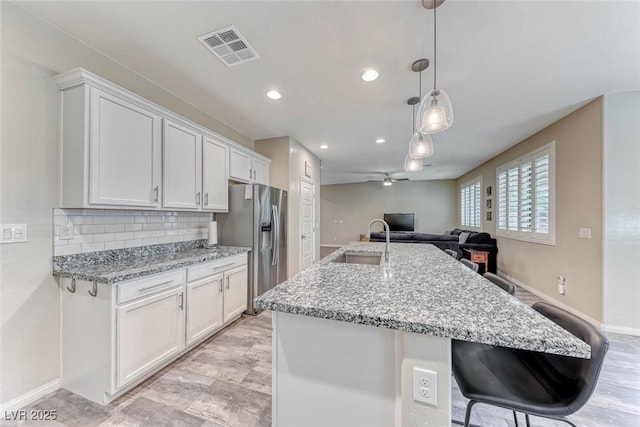 kitchen featuring white cabinetry, decorative light fixtures, stainless steel fridge with ice dispenser, and sink