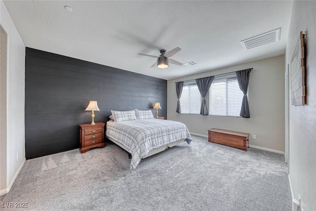 carpeted bedroom featuring ceiling fan, wooden walls, and a textured ceiling