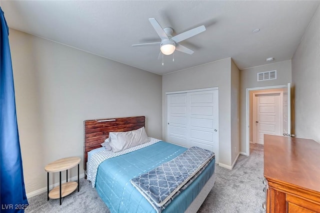 bedroom featuring light colored carpet, ceiling fan, and a closet