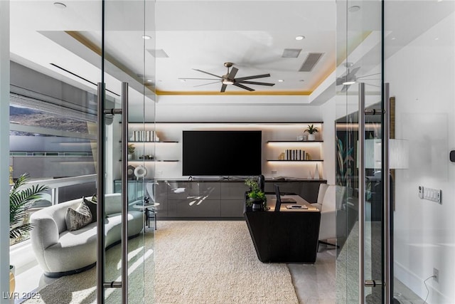 living room featuring ceiling fan and a raised ceiling