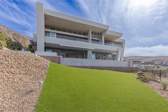 rear view of house featuring a mountain view and a lawn