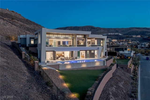 back of property with a balcony, a yard, a mountain view, and a patio area