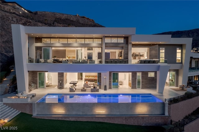 rear view of property with an outdoor living space, a mountain view, a pool with hot tub, and a patio