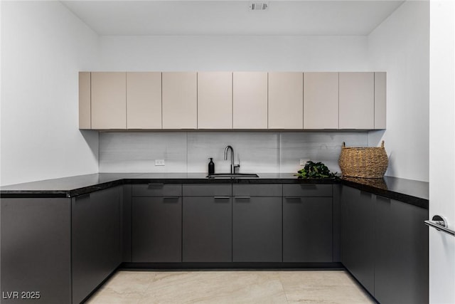 kitchen featuring gray cabinetry, sink, tasteful backsplash, and dark stone countertops