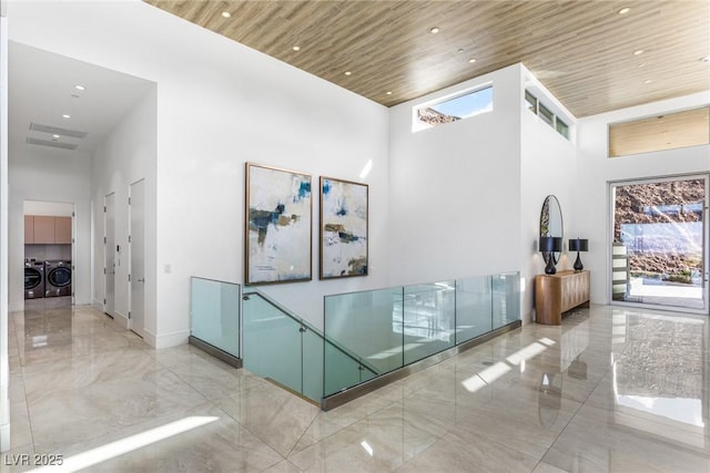 corridor featuring washing machine and clothes dryer, wooden ceiling, and a towering ceiling