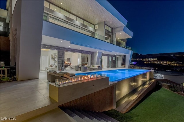 pool at twilight with an outdoor kitchen and a patio area