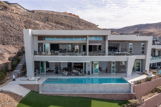 rear view of property with a fenced in pool, a patio, and a mountain view