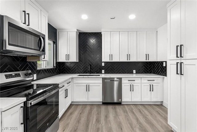 kitchen with sink, stainless steel appliances, light stone countertops, light hardwood / wood-style floors, and white cabinets