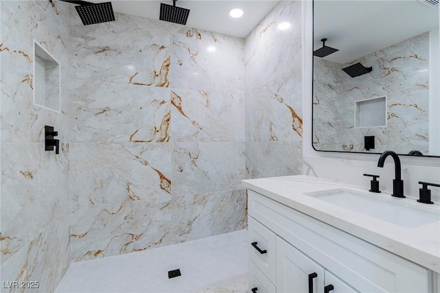 bathroom featuring tiled shower, vanity, and tile walls