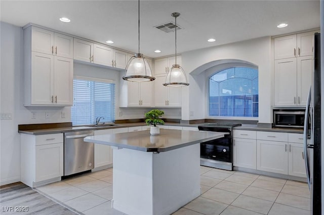 kitchen featuring sink, white cabinetry, decorative light fixtures, a center island, and stainless steel appliances