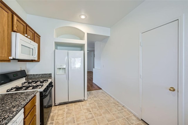 kitchen with white appliances and dark stone counters