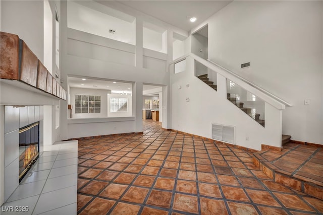 unfurnished living room featuring tile patterned flooring and a towering ceiling