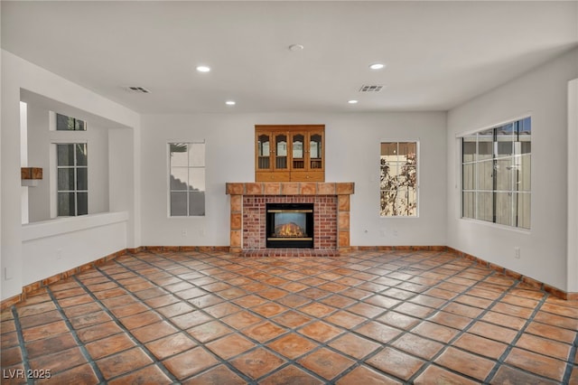 unfurnished living room featuring a brick fireplace and tile patterned floors