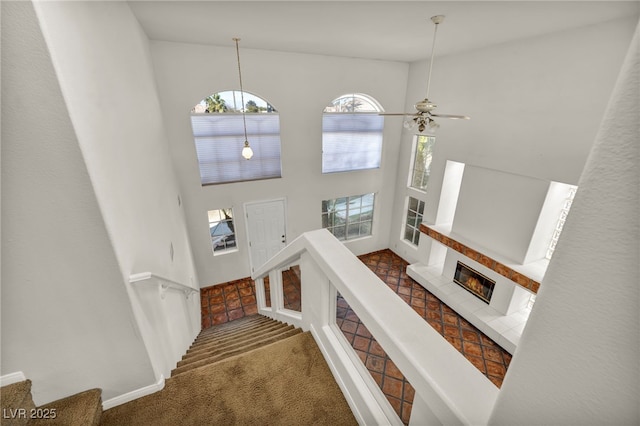 stairs with a tile fireplace, carpet flooring, and a towering ceiling