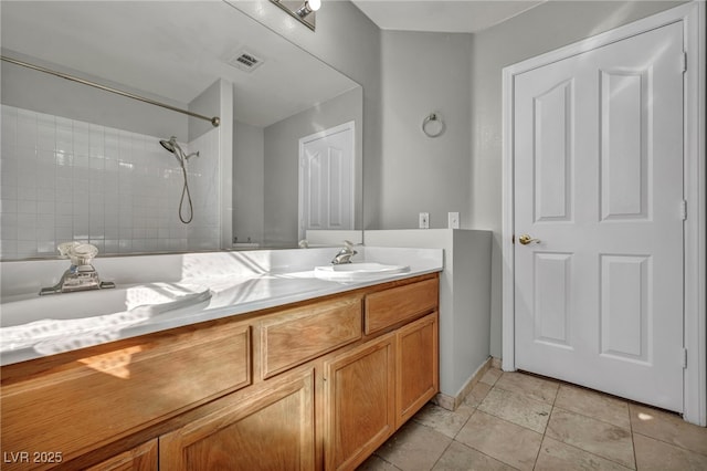 bathroom with vanity, a tile shower, and tile patterned floors