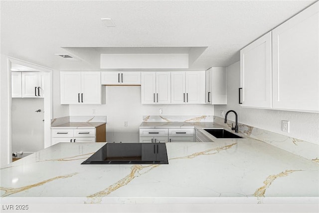 kitchen featuring white cabinetry, black electric stovetop, light stone countertops, and sink