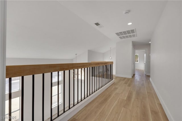 hall with vaulted ceiling and light hardwood / wood-style floors