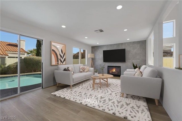 living room featuring light hardwood / wood-style floors, a wealth of natural light, and a large fireplace