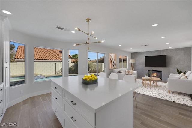 kitchen featuring a center island, light hardwood / wood-style flooring, white cabinets, and decorative light fixtures