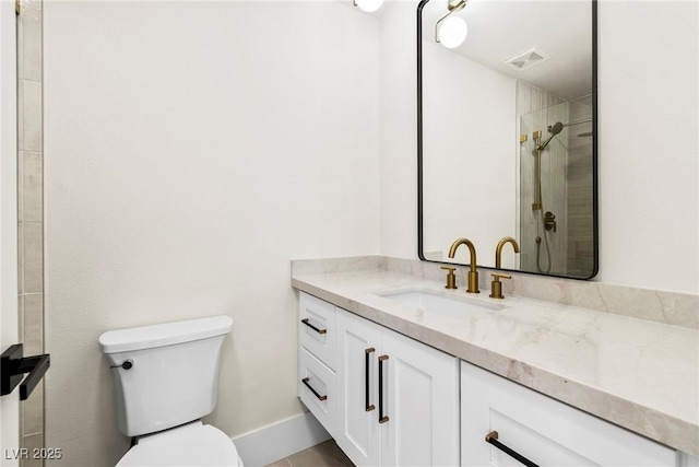 bathroom featuring vanity, tiled shower, and toilet