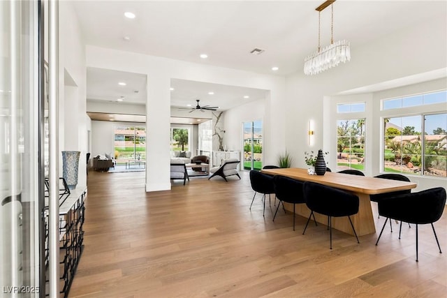 dining area with ceiling fan with notable chandelier and light hardwood / wood-style floors