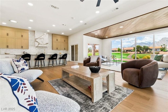 living room featuring ceiling fan, a mountain view, and light wood-type flooring