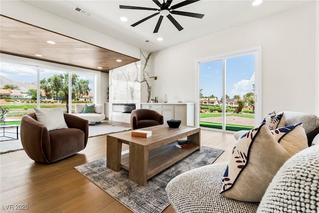 living room with ceiling fan, a fireplace, and light hardwood / wood-style floors