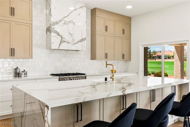 kitchen with light stone counters, decorative backsplash, a breakfast bar, and a center island with sink