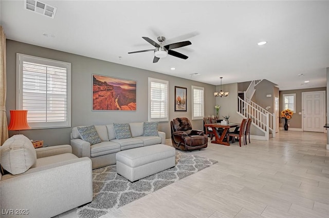 living room with ceiling fan with notable chandelier