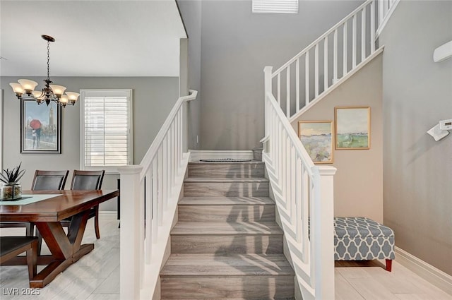 staircase with wood-type flooring and a chandelier