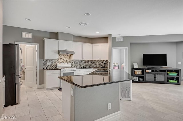 kitchen featuring white cabinets, sink, a center island with sink, and stainless steel fridge