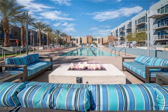 view of pool featuring a patio area and an outdoor living space with a fire pit