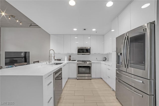 kitchen with white cabinetry, appliances with stainless steel finishes, sink, and decorative backsplash