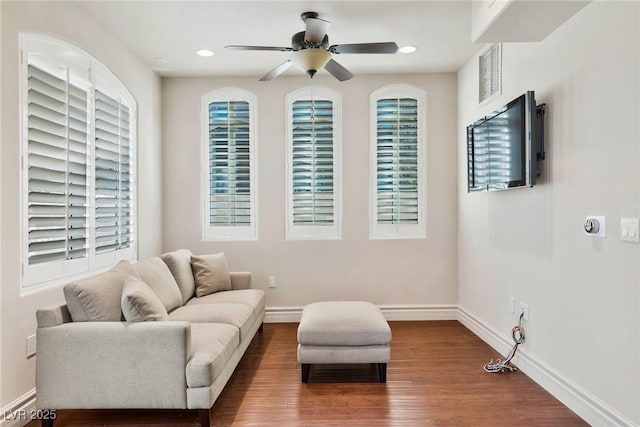 sitting room with baseboard heating, ceiling fan, wood-type flooring, and plenty of natural light