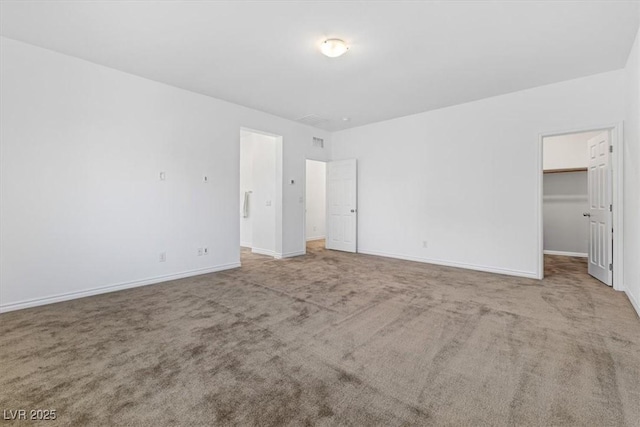 unfurnished bedroom featuring a walk in closet and carpet flooring