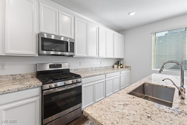 kitchen featuring appliances with stainless steel finishes, sink, and white cabinets