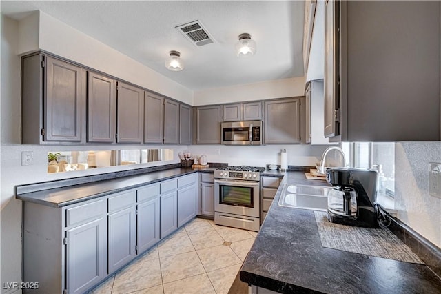 kitchen with gray cabinetry, sink, stainless steel appliances, and light tile patterned flooring