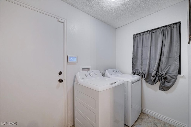 laundry room featuring washing machine and dryer, light tile patterned flooring, and a textured ceiling