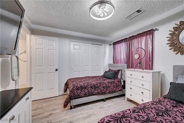 bedroom featuring a closet, light hardwood / wood-style flooring, and a textured ceiling