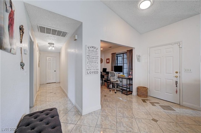 entrance foyer featuring vaulted ceiling, light tile patterned floors, and a textured ceiling