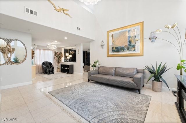 living room featuring light tile patterned flooring, a towering ceiling, and a chandelier