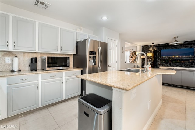 kitchen featuring appliances with stainless steel finishes, sink, a center island with sink, and backsplash