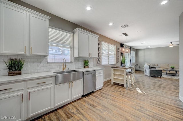 kitchen featuring a sink, visible vents, white cabinets, light wood-type flooring, and dishwasher