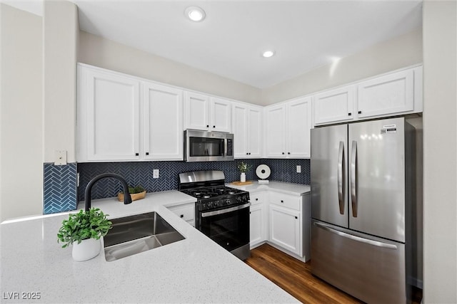 kitchen featuring sink, appliances with stainless steel finishes, backsplash, white cabinets, and dark hardwood / wood-style flooring