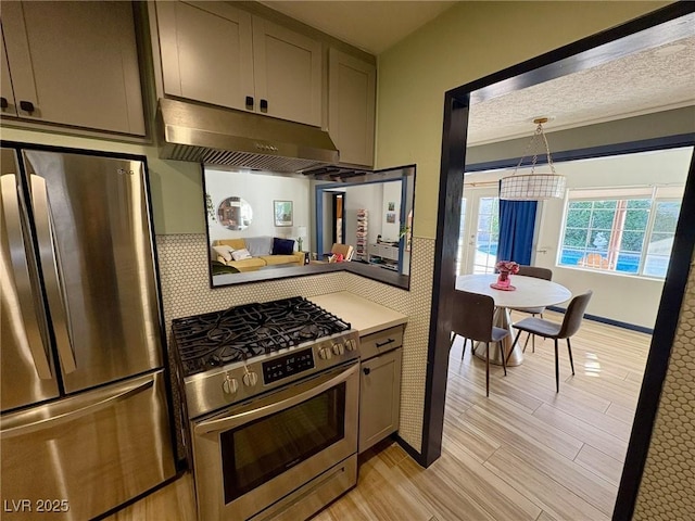 kitchen featuring appliances with stainless steel finishes, gray cabinetry, exhaust hood, a textured ceiling, and light hardwood / wood-style flooring