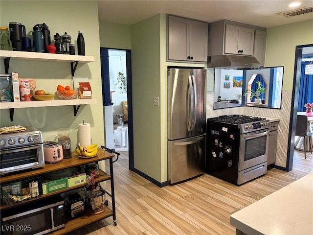 kitchen with gray cabinets, stainless steel appliances, and light hardwood / wood-style floors